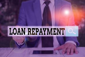 Man with a tablet and the words 'loan repayment' suggesting loan repayement hacks
