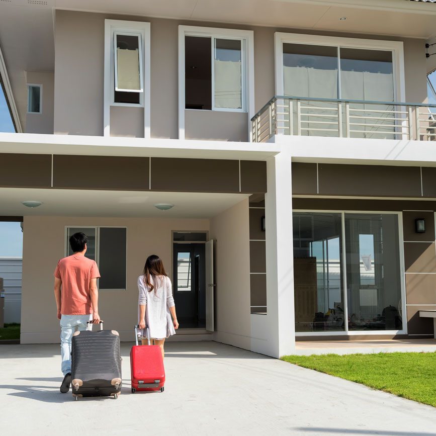 Young couple moving into a home with luggage after getting a Foreigner Loan Singapore